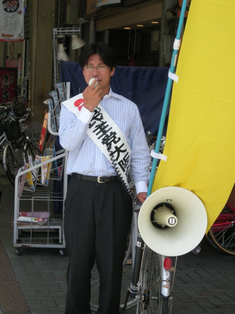 自転車で街宣する熊田氏